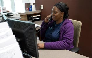 Black female sitting at a desk talking on an office phone